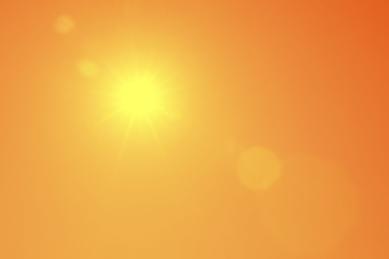 Bright sun in orange sky during hot summer weather